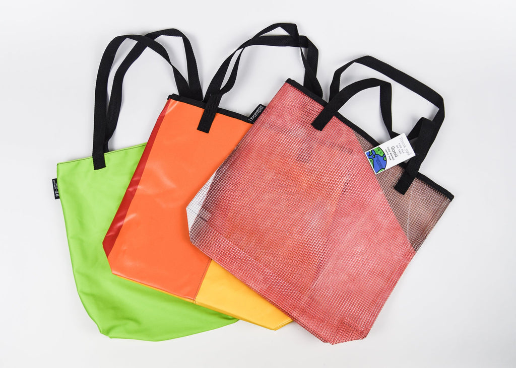 Four colorful tote bags with black handles on a white background - Esperanza sustainably made bags