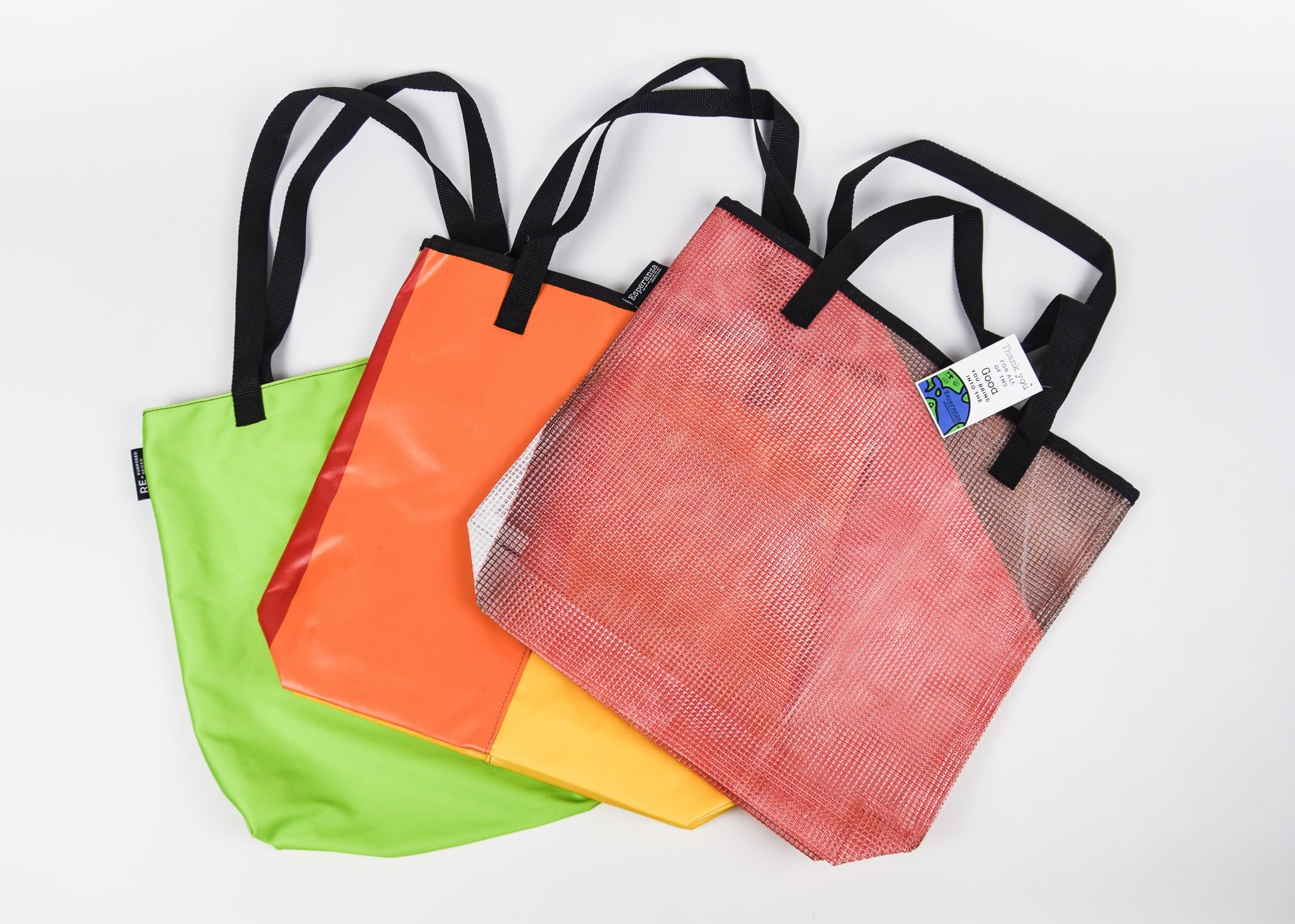 Four colorful tote bags with black handles on a white background - Esperanza sustainably made bags