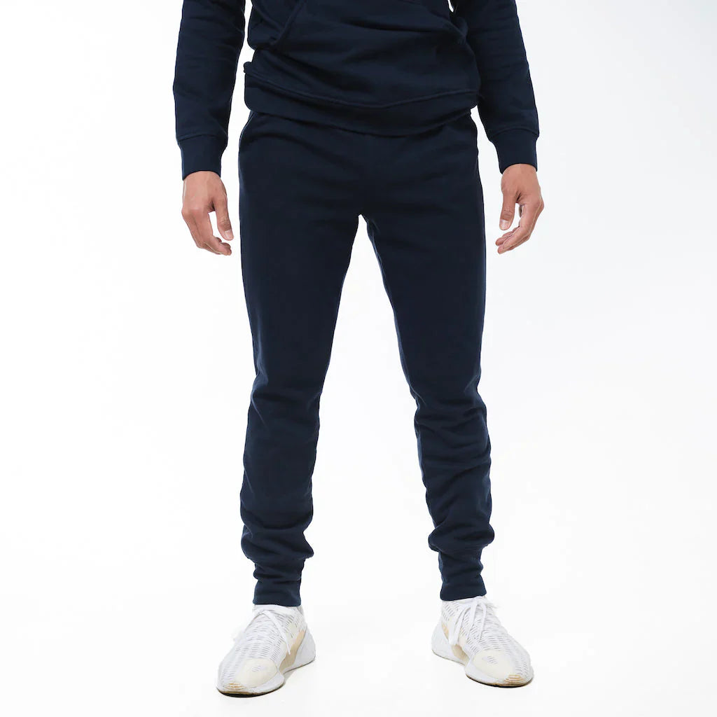 Person wearing navy blue tracksuit with white sneakers on a white background