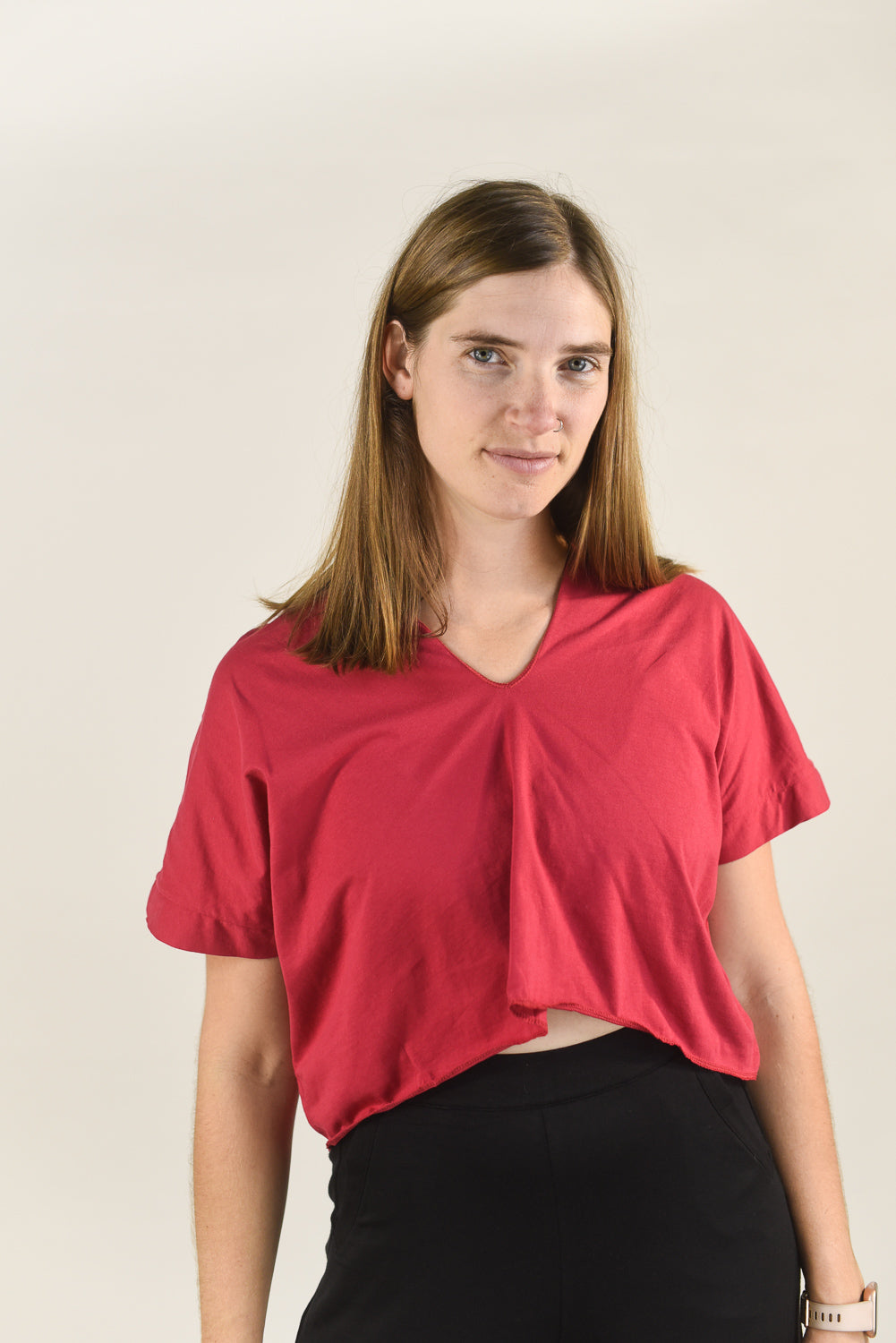 Woman wearing a red top and black pants against a plain background