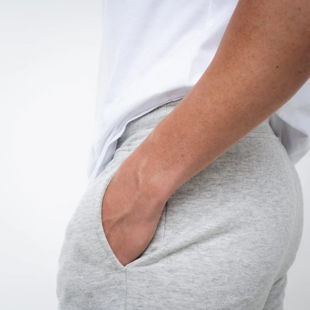 Person wearing gray sweatpants with a white shirt on a light gray background