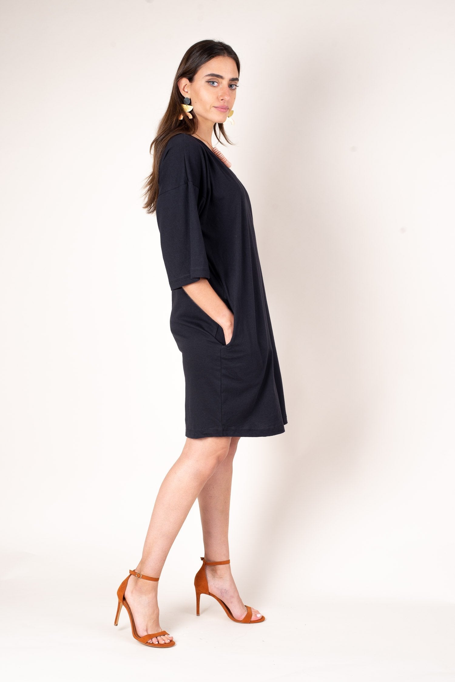 A side view of the airy fit of the black veha t-shirt style dress with deep side pockets to easily stash essentials.